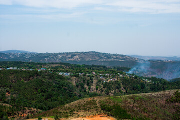 Obraz premium Smoky due to forest fire in hills and a distant landscape under a blue sky in Meghalaya .