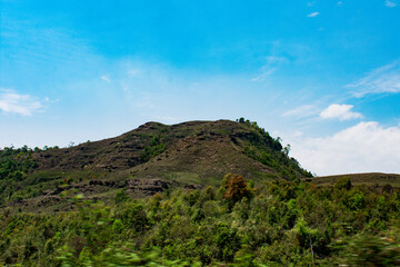 Lush green hills under a bright blue sky in Meghalaya. 