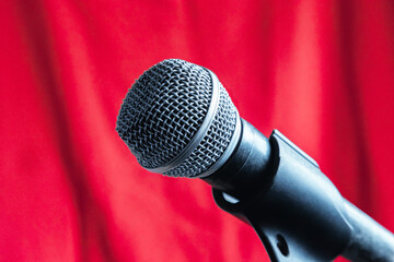Dynamic microphone on a microphone stand against a red curtain background close-up, microphone for...