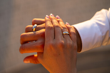 Hands Joined in Love Wearing Wedding Rings at Sunset