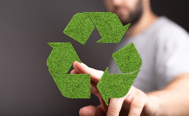 Eco-friendly recycling concept.  Man interacts with a green grass recycling symbol. Sustainable...
