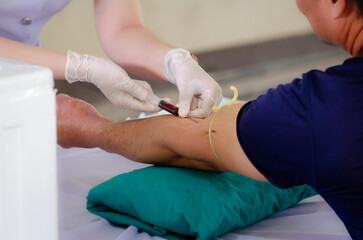 Close up nurse pricking needle syringe in the arm patient drawing blood sample for blood test ,...