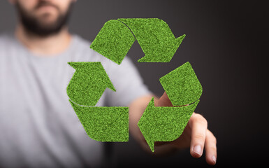 Eco-friendly concept image. Man interacts with a recycling symbol made of grass.