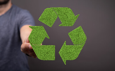 Eco-friendly concept. Man holding a recycling symbol made of grass. Sustainable living.