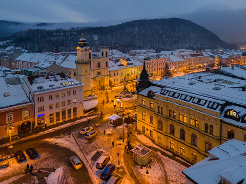 Aerial view of the illuminated N&Atilde;&iexcl;mestie SNP square, adorned with snow-dusted buildings beneath a twilight sky, Bansk&Atilde;&iexcl; Bystrica, Banskobystrick&Atilde;&frac12; kraj, Slovakia.