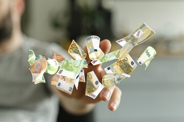 Close-up of a hand catching many Euro bills. Concept of finance, wealth, and success.