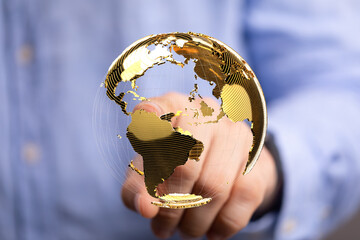 High-quality stock photo of a person interacting with a golden globe, representing global...