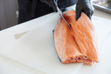 Chef slicing a big salmon meat in the kitchen
