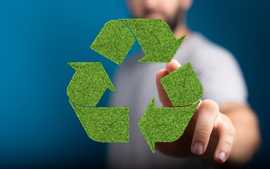 Eco-friendly concept image. Person interacts with a recycle symbol made of green grass.