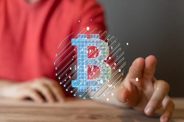 Close-up of a person's hand interacting with a digital Bitcoin symbol. Cryptocurrency, finance,...