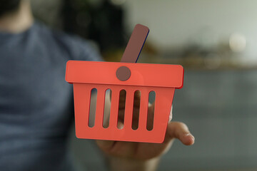 Modern ecommerce concept. Red shopping basket icon on hand. Digital marketing and online sales.