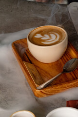 Cup of latte with rosette latte art on wooden tray and spoon. Great for coffee shop branding,...