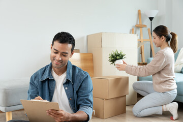 Move house, relocation. Husband using household checklist for new apartment Inside the room are...