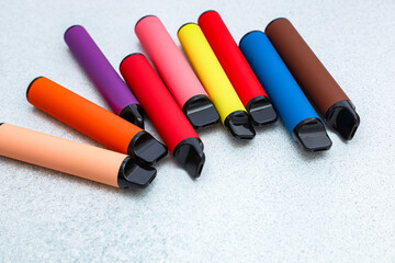 Colorful collection of vape pens arranged on a gray surface in a modern setting