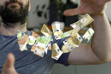 A man joyfully surrounded by flying Euro bills. Success, wealth, abundance concept.