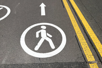 Pedestrian crosswalk symbol on city street with directional arrow for safe walking paths