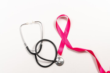 Pink ribbon symbolizing breast cancer awareness with stethoscope on white background. Medical and...