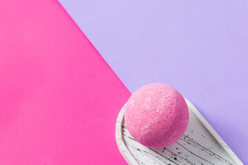 Colorful bath bomb on a stylish plate against vibrant pink and purple backdrop