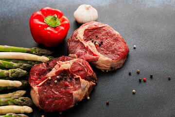 Freshly prepared steak with colorful vegetables on a black cutting board in a kitchen setting