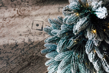 Decorated artificial Christmas tree with lights and cozy rug in warm indoor setting