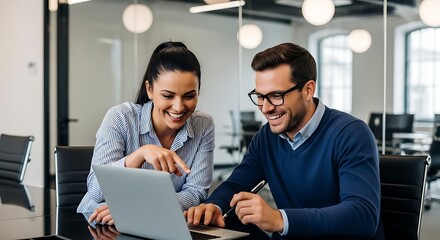 Two smiling coworkers working on a laptop together in a modern office environment