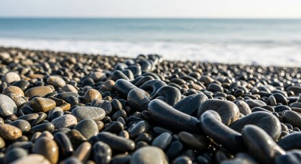 Obraz premium Smooth Wet Pebbles on Seashore with Blurred Ocean Horizon Landscape