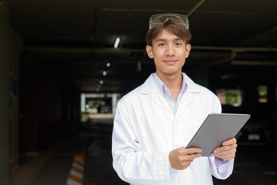 Young scientist student researcher wearing lab coat using tablet computer