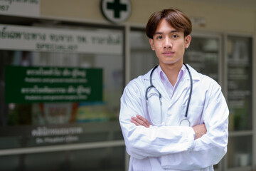 Young healthcare worker wearing lab coat in front of medical clinic