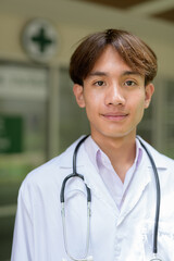 Young healthcare worker wearing lab coat in front of medical clinic