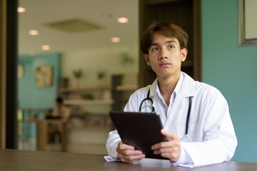 Young healthcare worker wearing lab coat sitting inside clinic library