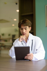 Young healthcare worker wearing lab coat sitting inside clinic library