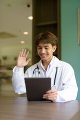 Young healthcare worker wearing lab coat sitting inside clinic library