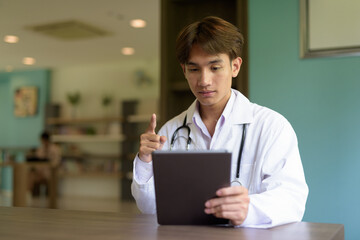 Young healthcare worker wearing lab coat sitting inside clinic library