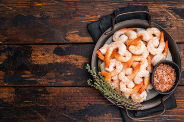 A plate of shrimp with a black bowl of salt and pepper. The shrimp are arranged in a way that they...