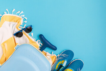 Children's beach essentials including  sunglasses, water shoes, suitcase and towel.