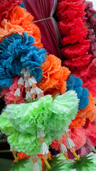 Close-up of vibrant flower garlands and fabric tied to the prow of a traditional Thai longtail boat. These offerings are part of local spiritual practices to bless the boat and ensure safe travels. Sh