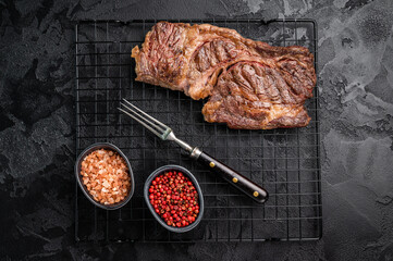 BBQ grilled Chuck eye roll steak, prime beef meat on a steel rack. black background. top view