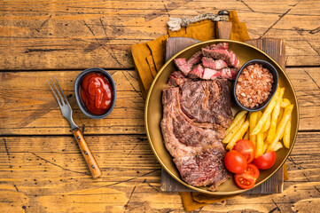 A juicy Grilled Chuck eye roll steak and garnish  with french fry on a plate. wooden background....