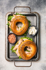 Fresh healthy bagel sandwich with smoked salmon, lettuce and cream cheese on a tray. gray...