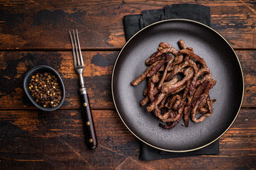 BBQ Fried beef tender strips, sliced steak in a plate. wooden background. top view