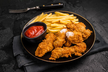 Deep fried chicken strips, sticks with french fry and sauce. black background. top view