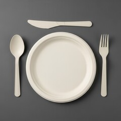 Disposable plate with spoon, knife, and fork on grey background