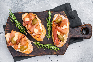 Tapa with Jamon cured ham, parmesan cheese and olives. grey background. top view
