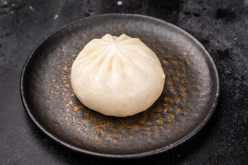 Chinese Steam Bao bun with meat on plate with chopsticks. black background. top view