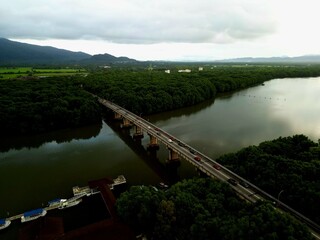 Morning traffic on bridge with river and mangrove area.
