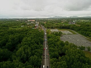 Morning traffic on bridge with river and mangrove area.