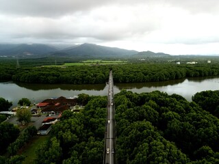 Morning traffic on bridge with river and mangrove area.