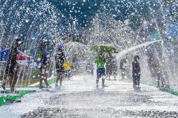 Children playing among the stream of water pouring from the park's floor fountain in the summer