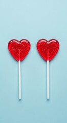 Two red heart shaped lollipops on blue background