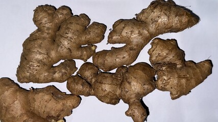 Several ginger roots are arranged on the surface of a white table evenly